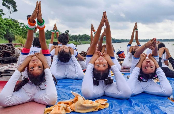 Girls perform yoga postures on the bank of Hooghly River on the occasion of International Day of Yoga, at Santipur in Nadia, Sunday, June 21, 2020. (PTI Photo)